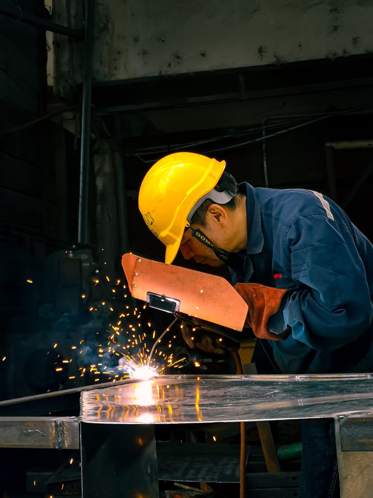 automotive A skilled welder performs metalwork in an industrial workshop, creating sparks.